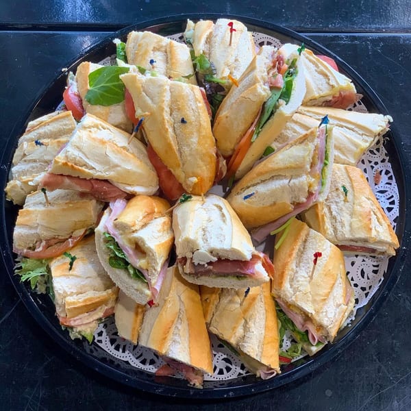 A platter of baguette sandwiches filled with deli meats, cheese, lettuce, and tomato.