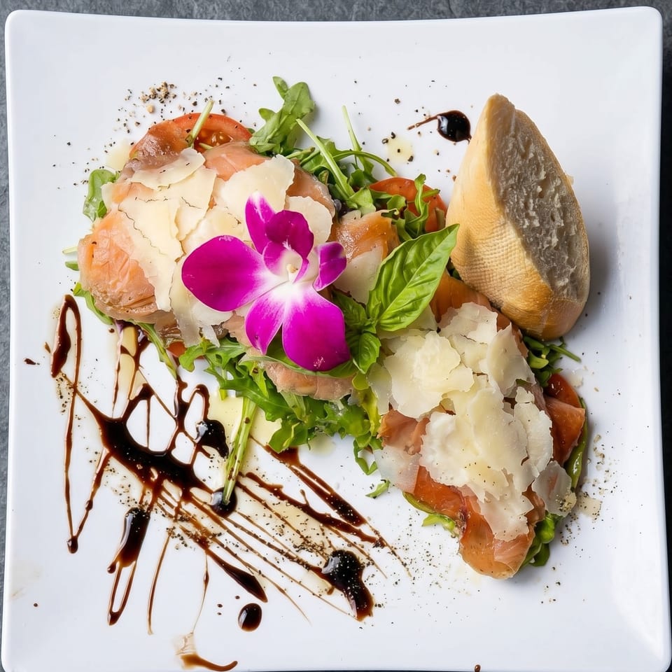 Smoked salmon carpaccio with arugula, parmesan, basil, and balsamic glaze, garnished with an orchid.